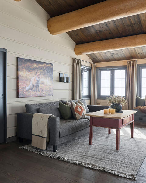 Myke tekstiler skaper en varm og innbydende atmosfære i stua, og gir rommet en følelse av komfort og hygge. Tenk deg å komme inn fra en lang skitur og nyte varmen og komforten som denne hytta gir.